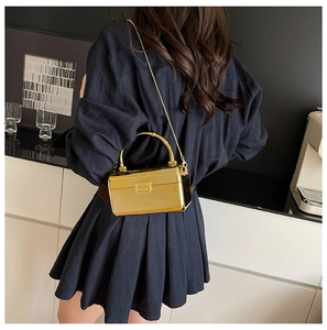 Detailed back view of a woman holding a metallic gold acrylic box bag with chain strap