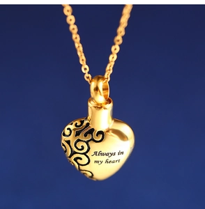 Macro detail of golden heart urn necklace with Always in my heart engraving on blue background