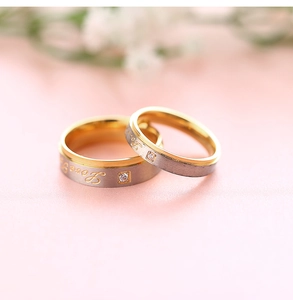 Nahaufnahme von zweifarbigen Edelstahl-Partnerringen mit Love-Gravur und kleinem Diamant