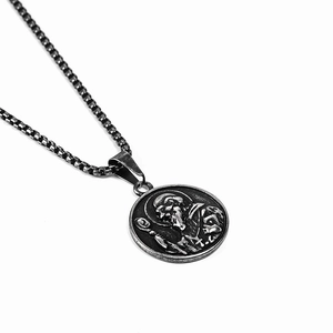 Detail showing vintage religious saint emblem pendant with oxidized steel box chain