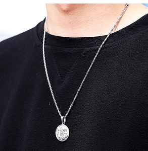 Macro shot of silver stainless steel religious coin pendant on a box chain for men