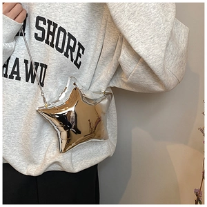 Detail of silver metallic star-shaped crossbody bag with slim chain strap on model