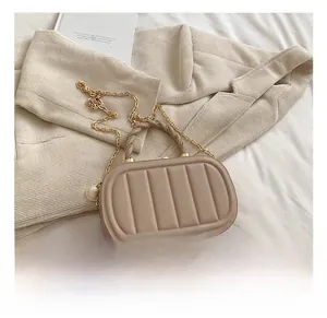 Detail of beige quilted crossbody bag with pearl charm and woven handle texture
