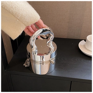 Close-up of a glossy silver cylindrical acrylic clutch with a metallic handle and chain strap