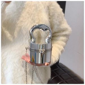 Detail of silver mirror cylinder handbag with sleek curved handle and metal chain strap