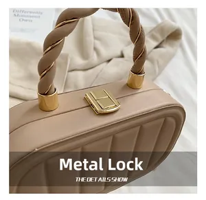 Detailed view of the gold clasp and twisted handle on this quilted cream box bag