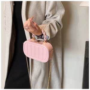 Detail of pink quilted handbag with gold chain strap and spiral leather handle