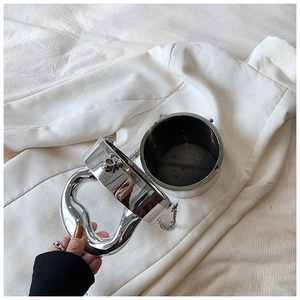 Detail of silver metallic cylinder bag showing liquid-effect handle and sleek chain strap