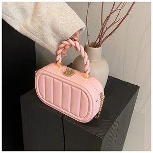 Detail of pink quilted handbag featuring a twisted woven handle and gold hardware lock