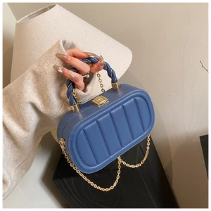 Close-up of blue quilted leather bag with elegant gold chain and knotted top handle