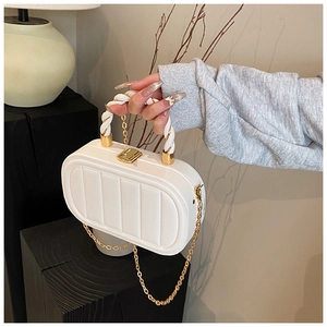 Detail of white quilted hard shell handbag with gold clasp and twisted top handle