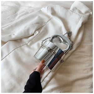 Detail of silver mirror finish cylindrical box bag with metallic chain and curved handle