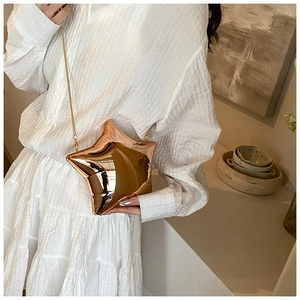 Close-up of a gold star-shaped crossbody bag with a sleek metallic finish and chain strap