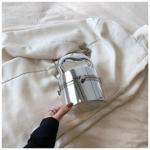 Detail of silver mirror acrylic barrel bag showing sleek metal handle and glossy finish