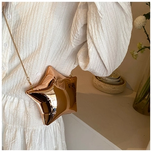 Close-up of rose gold star shaped evening bag with metallic chain on white dress