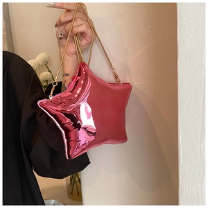 Macro shot of bright red star-shaped crossbody bag with glossy metallic finish and gold chain