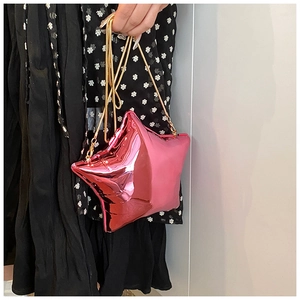Detail of pink metallic star-shaped evening bag with elegant gold chain strap