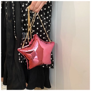 Detail of metallic pink star bag with golden chain strap on a floral dress