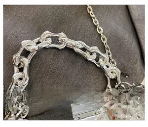 Detail view of the chunky silver metal chain handle and textured strap on a striped box bag