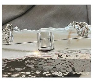 Close-up of silver metal box bag featuring hammered texture and secure metal lock