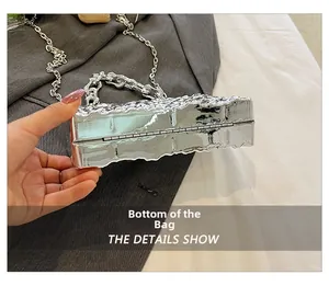 Detail view of the silver metallic evening bag showing the bottom hinge and texture
