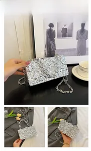 Detail view of silver textured box bag with metallic finish and chain shoulder strap