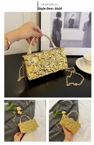 Detail of a gold box clutch featuring hammered metal texture and a chic arched handle