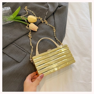 Detailed macro shot of the golden metallic striped texture on a luxury box evening bag