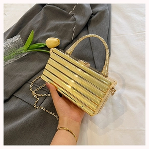 Detail of gold box clutch featuring horizontal stripes and diamond-studded handle