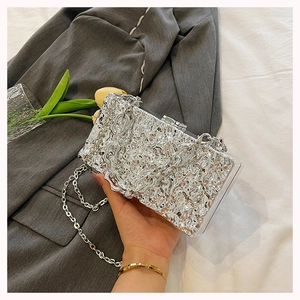 Close-up of a silver textured box clutch bag with metallic chain strap and lock