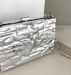 Detailsicht der silbernen Plissee-Clutch mit Hartschalen-Design und Metallkettenriemen