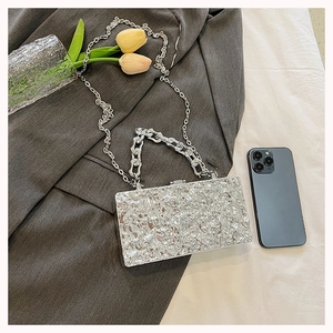 Close-up of silver rectangle box bag with molten texture, metal chain and top handle