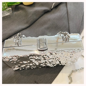 Close-up of silver rectangular chain bag with unique wrinkled metallic texture and clasp