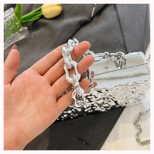 Close-up of a silver ripple texture evening bag with a chunky metal chain handle