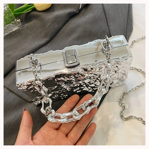 Close-up of silver box clutch featuring metallic hammered texture and dual chain straps