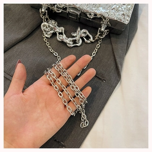 Detail of silver liquid metal box bag featuring unique wavy texture and dual chain straps