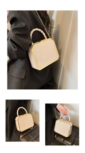 Detail of octagonal beige handbag with woven handle and gold metal trim finish