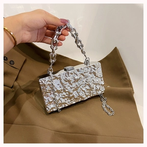 Detail of silver box bag featuring irregular hammered texture and thick geometric chain handle