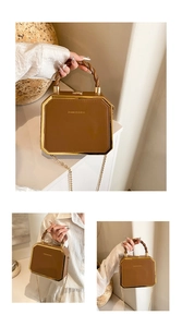 Detail of vintage brown square handbag featuring golden metal frame and chain strap