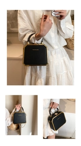 Detail of a black hexagonal leather handbag featuring gold metal edges and a chain strap