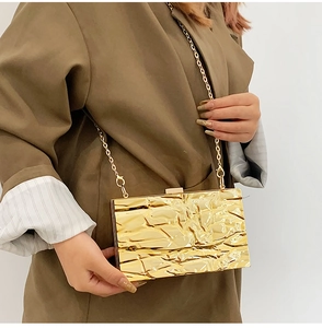 Detail der goldenen Abendtasche mit plissierter Metallstruktur und eleganter Kette