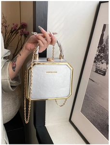 Detail of silver hexagonal box bag with gold floral handle and chic chain strap