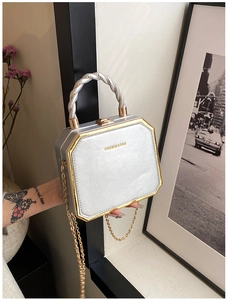 Macro view of silver geometric handbag with gold metal frame and twisted handle