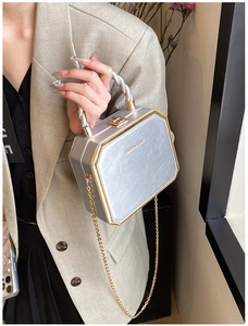 Close-up of a silver hexagonal crossbody bag with gold chain and metal top handle