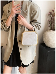 Detail of silver octagonal handbag with gold metal trim and twisted woven handle