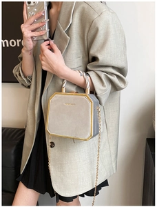 Close-up of octagon crossbody bag in light grey with gold metal trim and chain strap