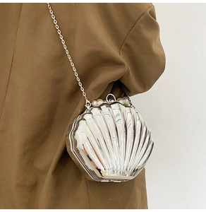 Detail of silver shell-shaped evening bag with mirror finish and pearl accents