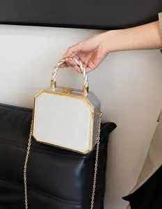 Detail of silver octagonal box bag with gold metal trim and twisted metallic handle