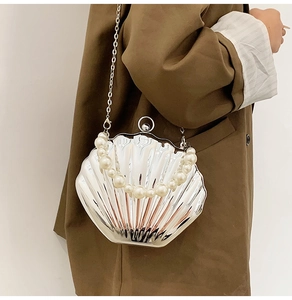 Detail of silver shell-shaped crossbody bag with pearl handle and metallic texture