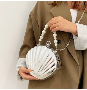 Detail of silver shell bag with metallic mirror finish and elegant pearl top handle